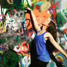 girl in dance pose by graffiti wall