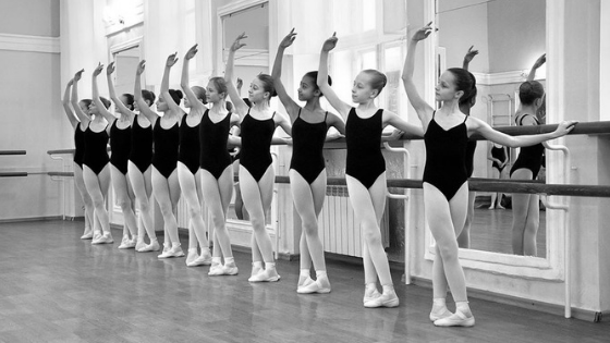 young ballet students standing in fifth position at the barre