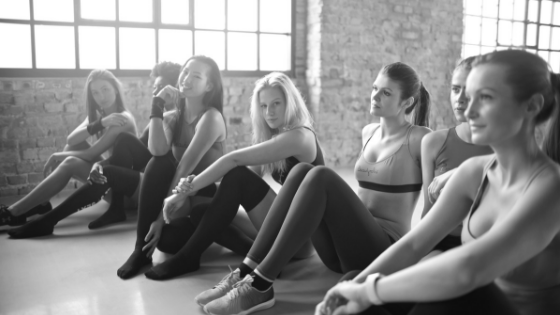 Six women sitting in a dance classroom