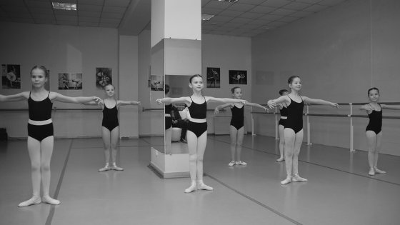 Young teen girls wearing leotards stand posed in a dance studio